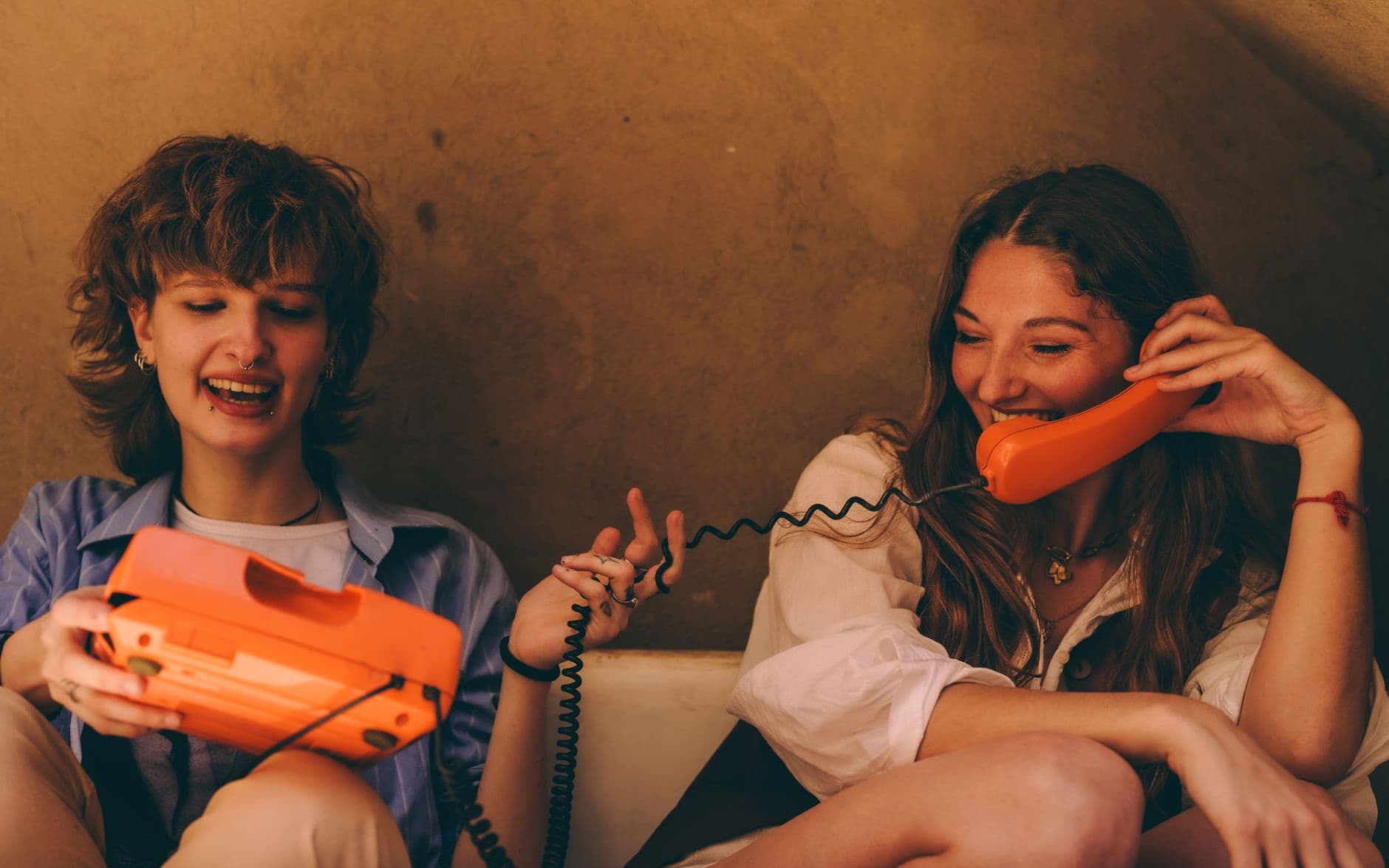 Two friends laughing together while looking at a phone